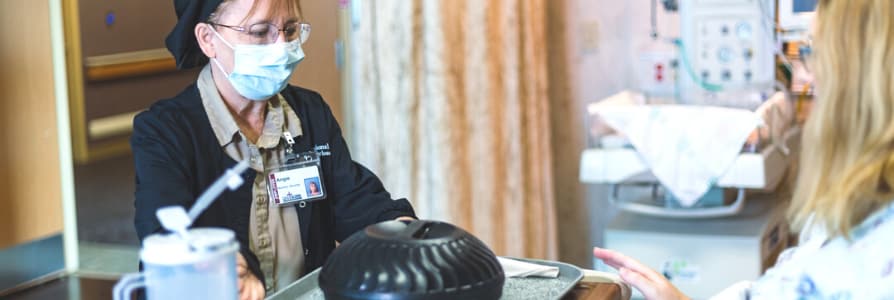 Nutrition employee bringing a meal to a patient room.