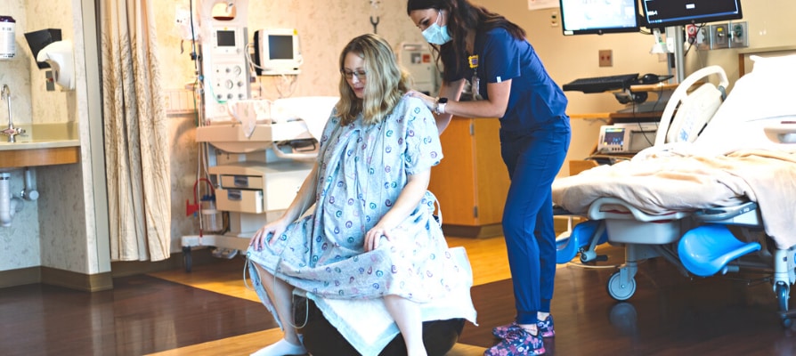 A mom in labor being comforted by a Faith Health labor and delivery nurse.