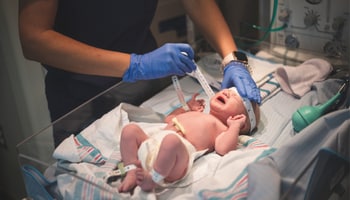 A newborn being measured by a Faith Health nurse.