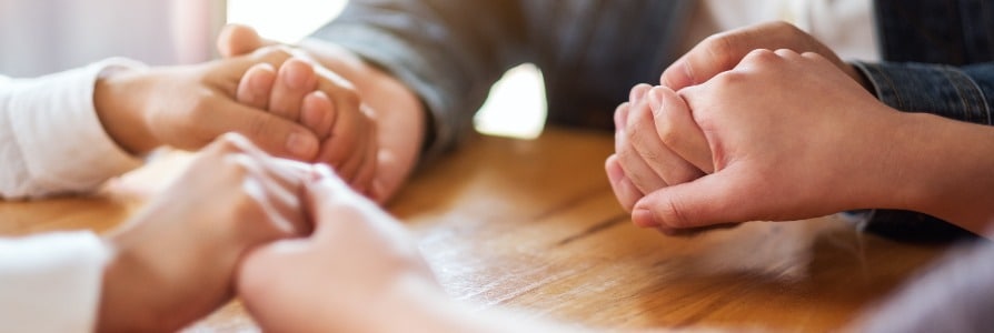 Group of people holding hands and praying