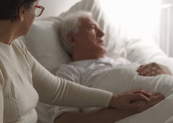 A family member sitting with a loved one who is receiving hospice care.
