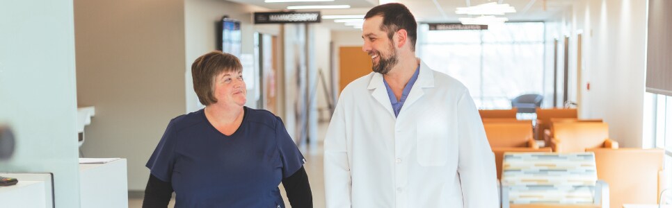 A provider with his nurse talking in the hallway.
