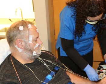 A sleep technologist preparing a patient for his sleep study.