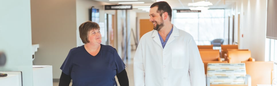 A provider with his nurse talking in the hallway.